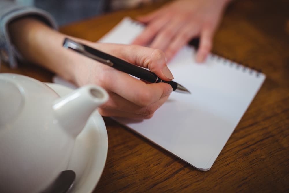 A woman writing a note enjoying tea